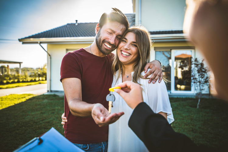 couple receiving keys from realtor after buying new construction home